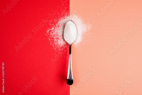 Fototapeta sugar with spoon on red and yellow background