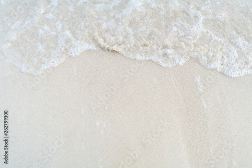 Soft wave with foam of ocean on the sandy beach