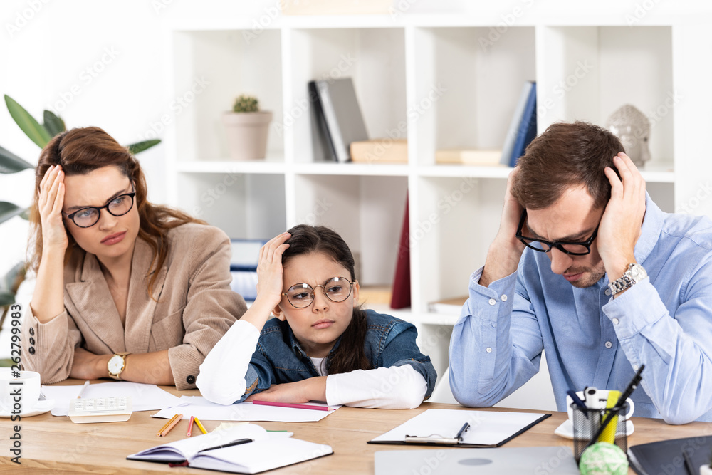 cute kid in glasses sitting with exhausted parents in office cute kid in glasses sitting with exhausted parents in office