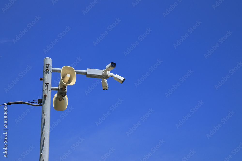 Loudspeakers and CCTV security cameras beach area on blue sky Loudspeakers and CCTV security cameras beach area on blue sky