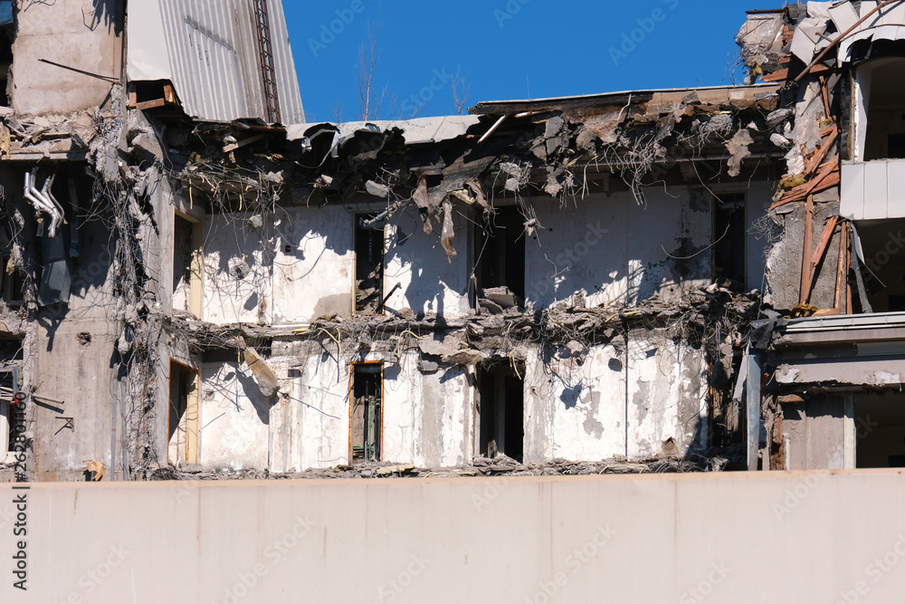 Demolished destructed building ruins. Demolition site in european city. Ruined house on a bright blue sky on a sunny day.