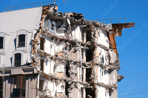 Demolished destructed building ruins. Demolition site in european city. Ruined house on a bright blue sky on a sunny day. © Arseny