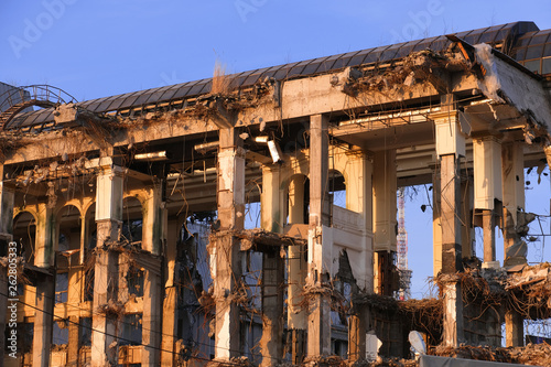 Demolished destructed building ruins. Demolition site in european city. Ruined house on a bright blue sky at sunset