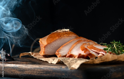Smoked breast chicken fillet whole and sliced on wooden board. Rustic natural food