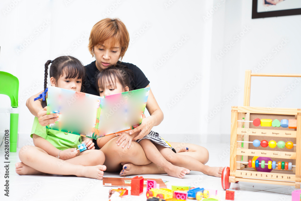 Fototapeta premium Mom is reading comic book with her daughters