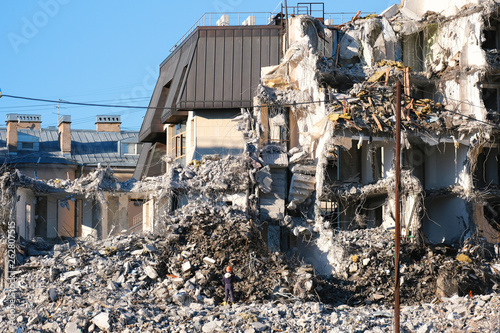 Demolished destructed building ruins. Demolition site in european city. Ruined house on a bright blue sky on a sunny day.