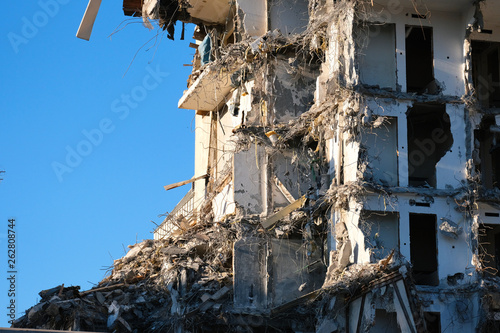 Demolished destructed building ruins. Demolition site in european city. Ruined house on a bright blue sky on a sunny day. © Arsenii