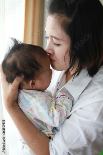 Mom is holding and kissing her baby with love