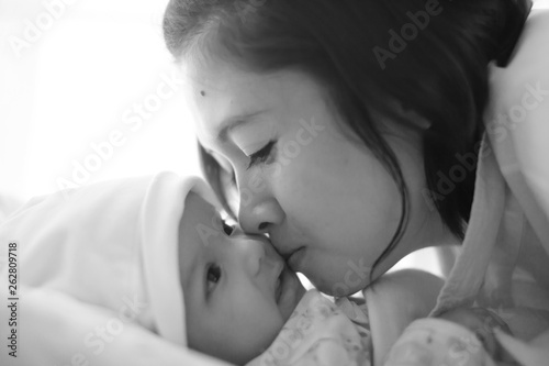 Mom is holding and kissing her baby with love