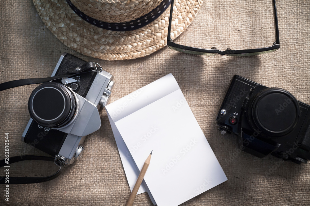 Notebook,cameras,sunglasses and a hat for travel