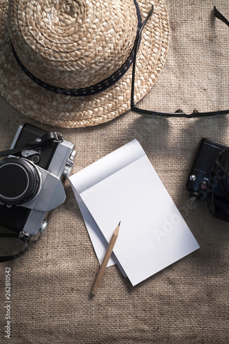 Notebook,cameras,sunglasses and a hat for travel