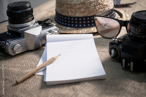 Notebook,cameras,sunglasses and a hat for travel
