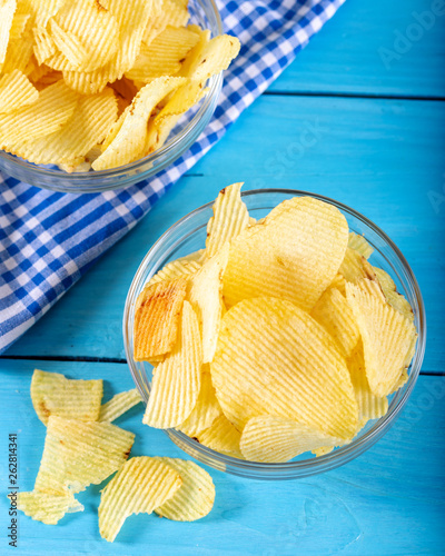 Potato chips in glass bowl on white background.