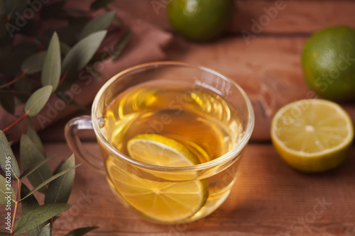 Cup of hot green tea with lime on the old wooden table