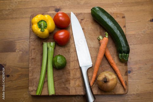 fresh vegetables on the cutting board and knife onion, tomatoes,carrot lemons., paprika, on wood background
