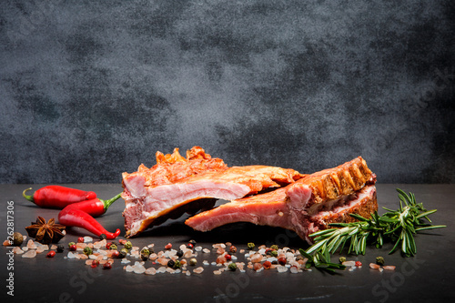 big pieces of smoked ribs with spices, rosemary and two chili peppers