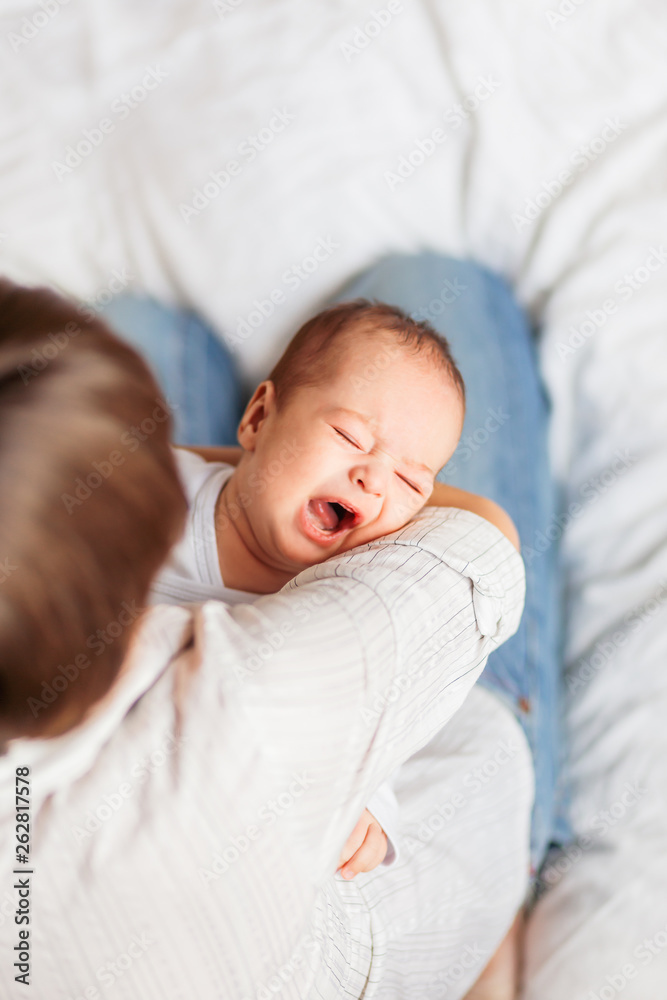 Woman holding a crying baby. Mother comforts her little son or daughter. Woman holding a crying baby. Mother comforts her little son or daughter.