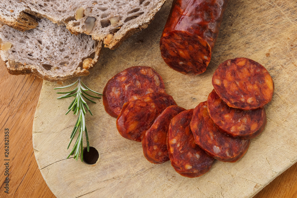 Iberian chorizo, Spanish chorizo or Spanish sausage cut into slices on a wooden board with rustic bread Iberian chorizo, Spanish chorizo or Spanish sausage cut into slices on a wooden board with rustic bread