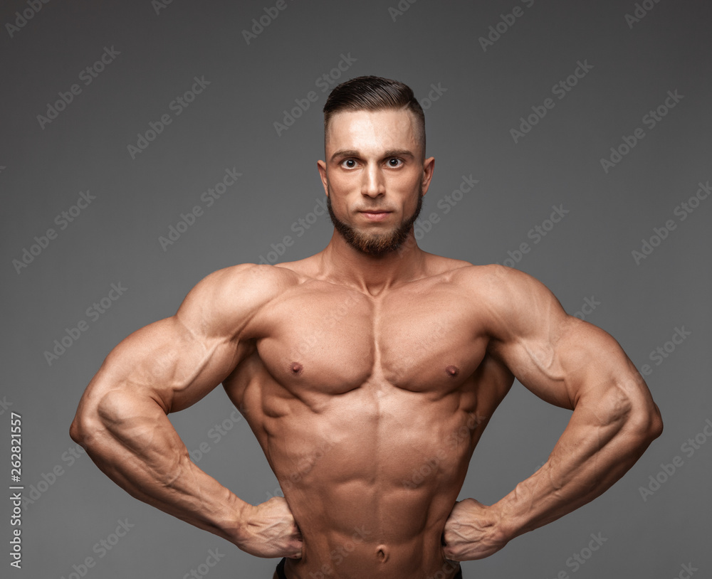 muscular super-high level handsome man posing on gray background
