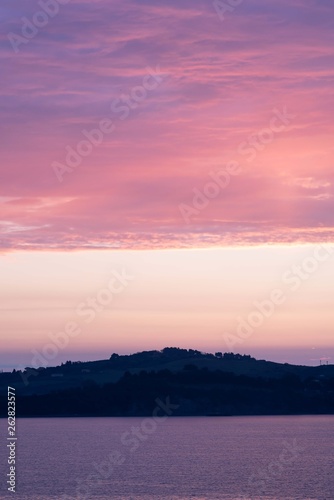 Sunup on Talamonaccio  view from Talamone  with a pink-orange sky full of clouds