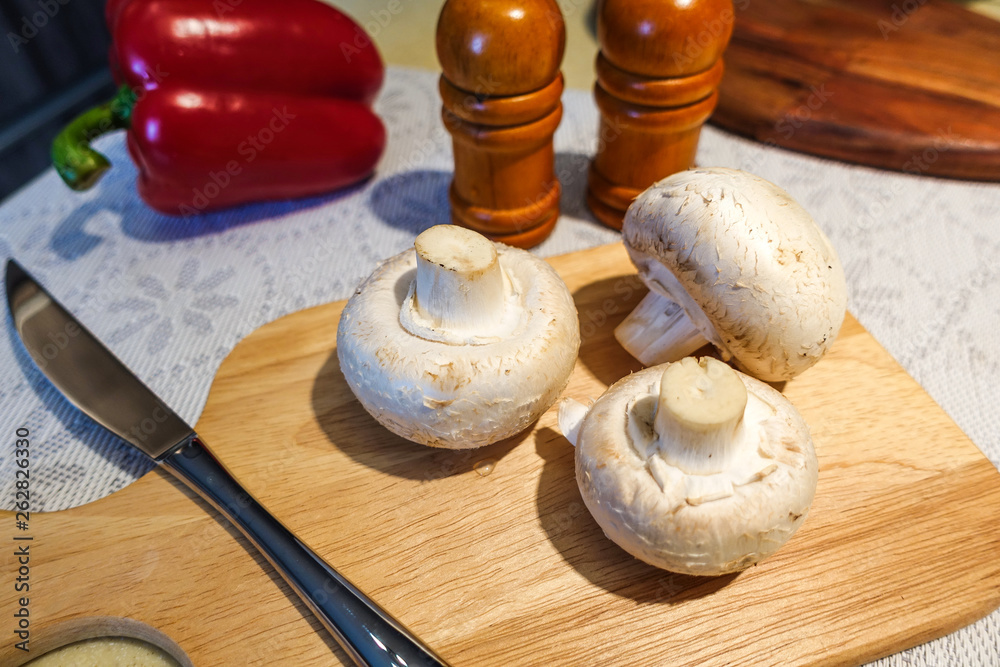 Fresh champignon mushrooms on a cutting board. Close-up. Vegetarian food.