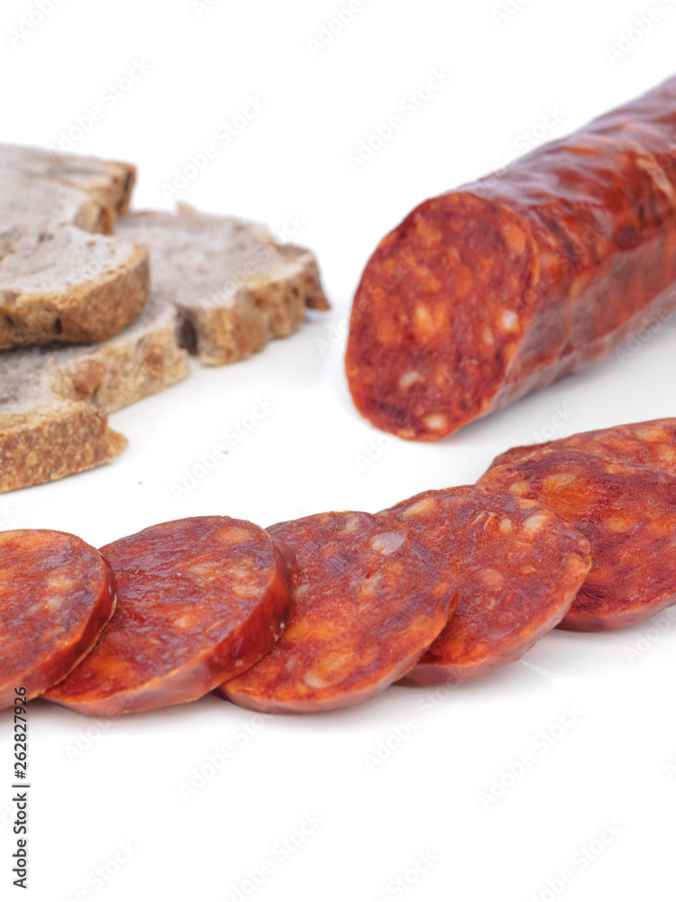 Iberian chorizo, Spanish chorizo or Spanish sausage with its slices placed one on another on a white background with its reflection with rustic bread Iberian chorizo, Spanish chorizo or Spanish sausage with its slices placed one on another on a white background with its reflection with rustic bread