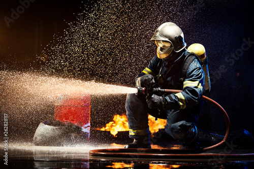 Anonymous fireman fighting fire with water photo