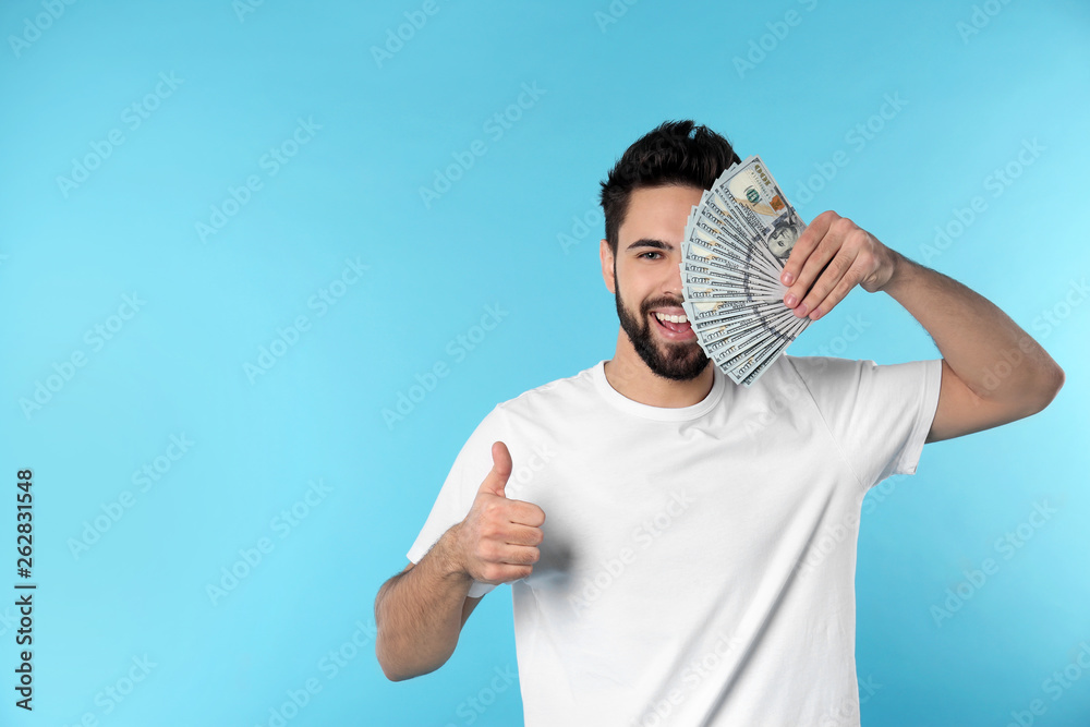 Portrait of happy young man with money on color background. Space for text Portrait of happy young man with money on color background. Space for text