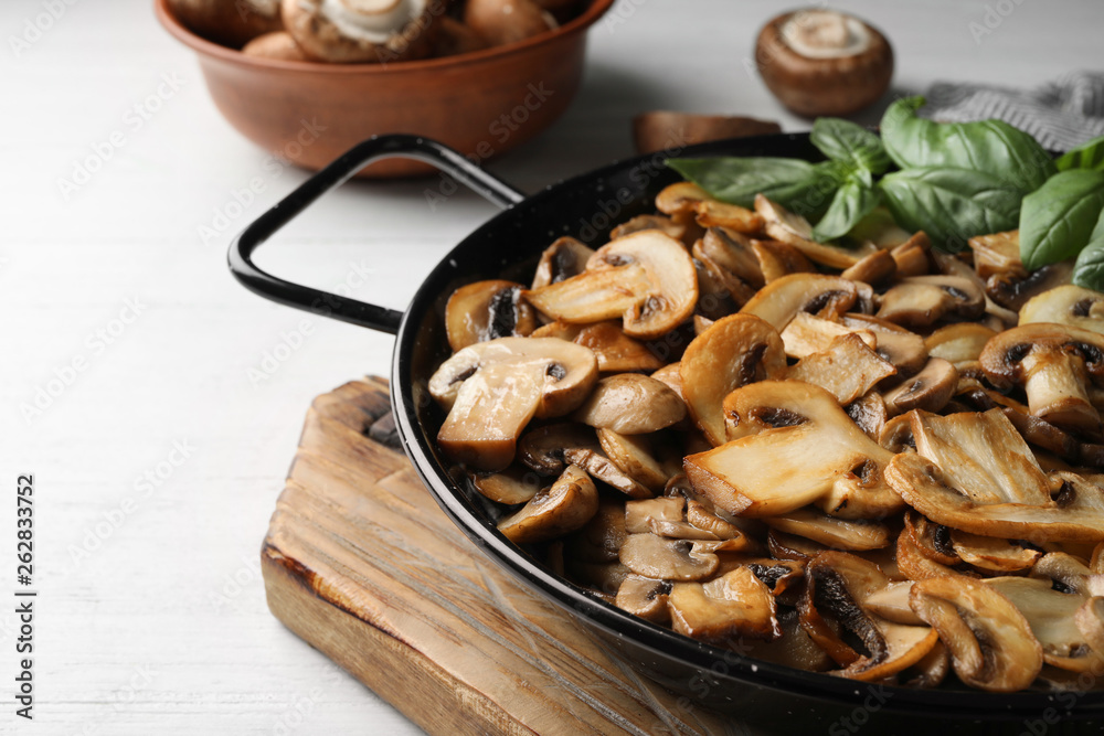 Delicious cooked mushrooms in frying pan on table. Space for text Delicious cooked mushrooms in frying pan on table. Space for text