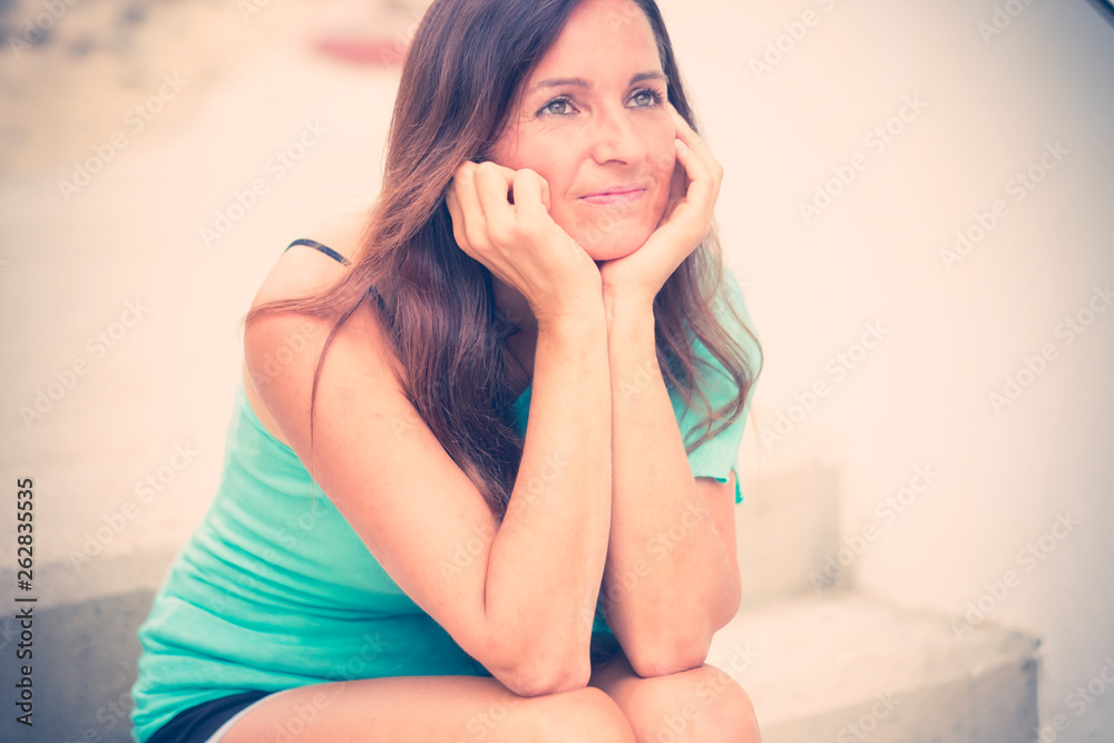 Thoughtful beautiful young woman with black long hair smile kindly whie sit down on a staris - people outdoor in his own thougths - cute caucasian female Thoughtful beautiful young woman with black long hair smile kindly whie sit down on a staris - people outdoor in his own thougths - cute caucasian female