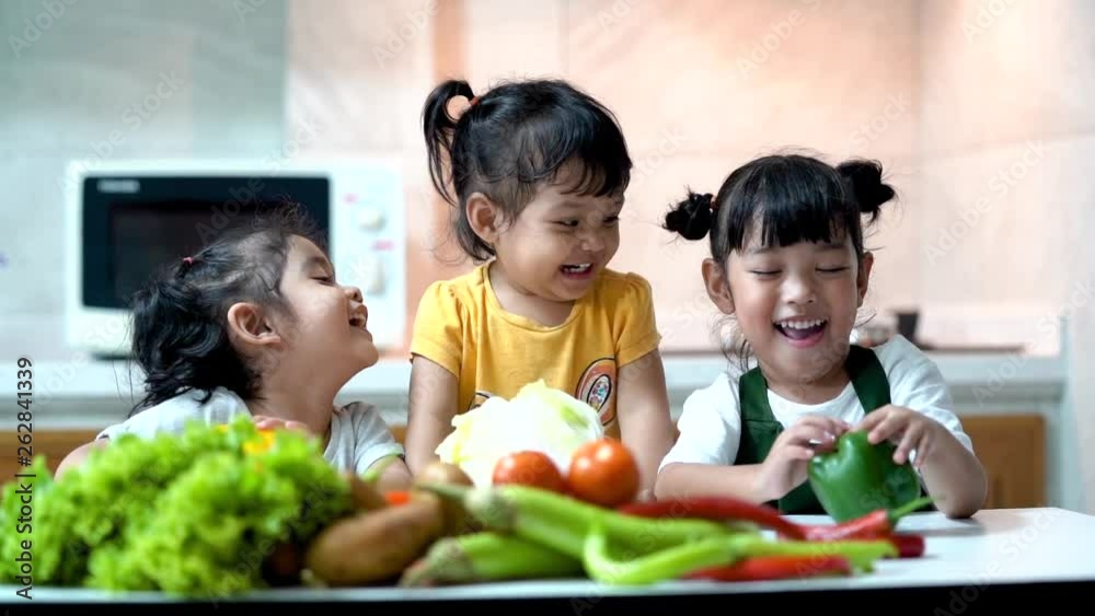 Happy children in the kitchen at home. Kid enjoy cooking the healthy food with variety of vegetable.