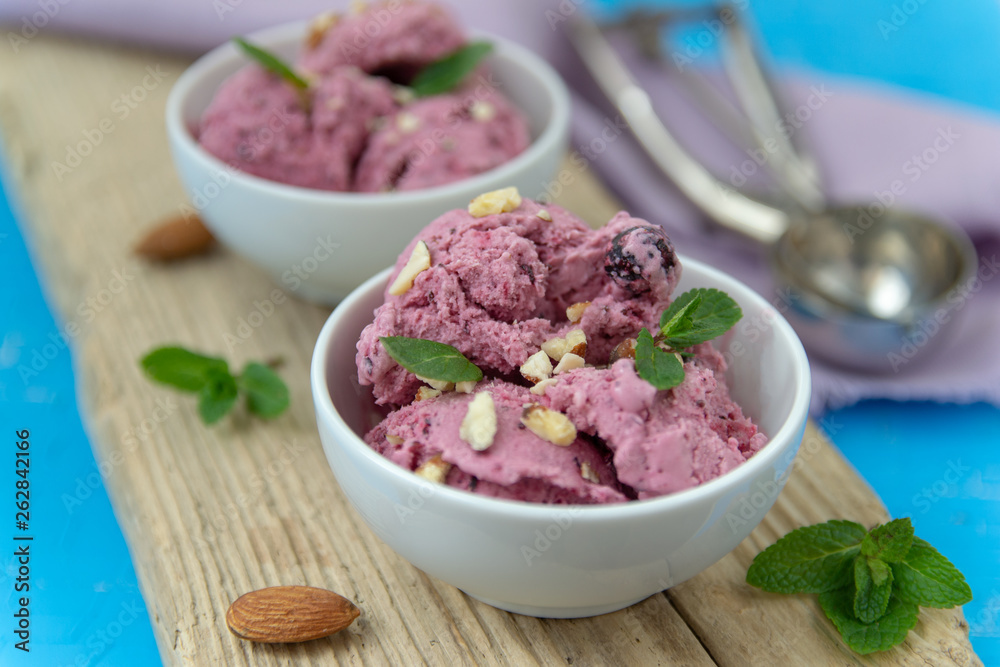 Ice cream with berries. Ice cream balls in a white bowl with nuts and mint.