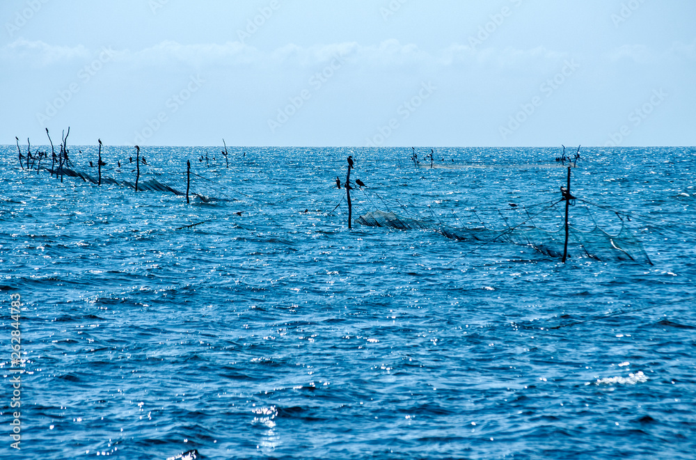Fishing trap equipment with fishing networks in blue sea waters on blue sky background