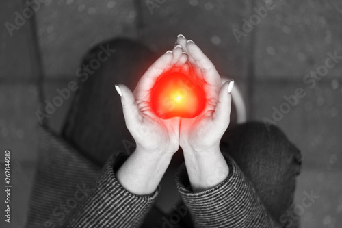 Black and white photo of woman holding on palms red heart staying on the knees. Declaration of love or Charity concept. photo