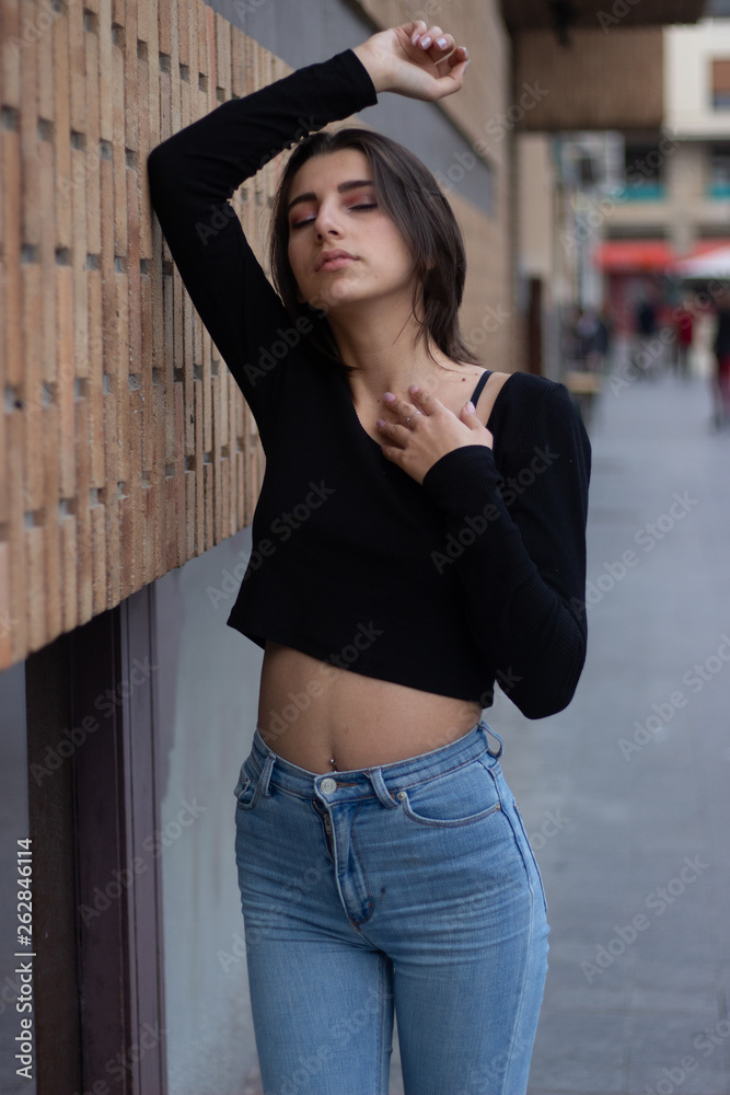 Hipster beautiful girl wearing blank t-shirt and jeans posing against