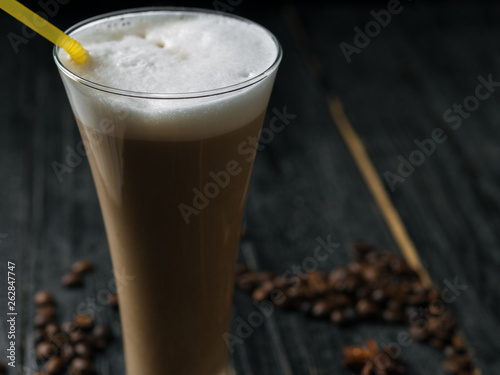 An elongated beautiful glass of latte coffee with a straw