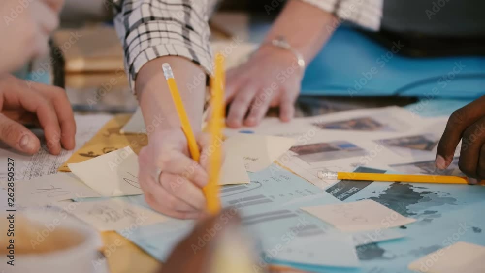 Teamwork at office table meeting, hands of multiethnic business colleagues working together with paper notes close-up. Teamwork at office table meeting, hands of multiethnic business colleagues working together with paper notes close-up.