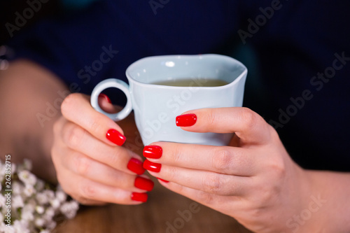 Beautiful female hand close up with red nails manicure write with pen Limited depth of field