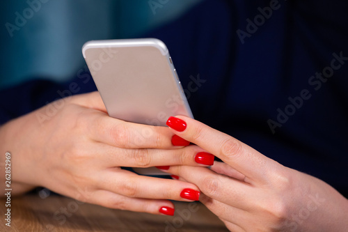 close-up  female hands with red manicure use a smartphone on a white background. Limited depth of field