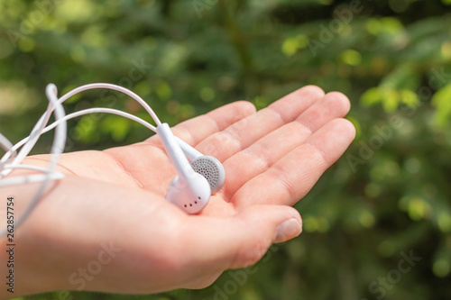 White headphones in the hand of a teenager