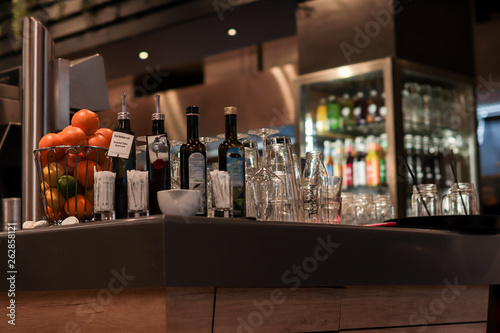 A bar with glasses, flashing and fruit on it in an atmosphere restaurant.
