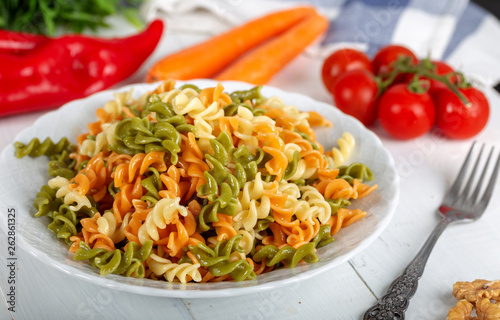 Multicolored pasta with vegetable on wooden background ve vegetables