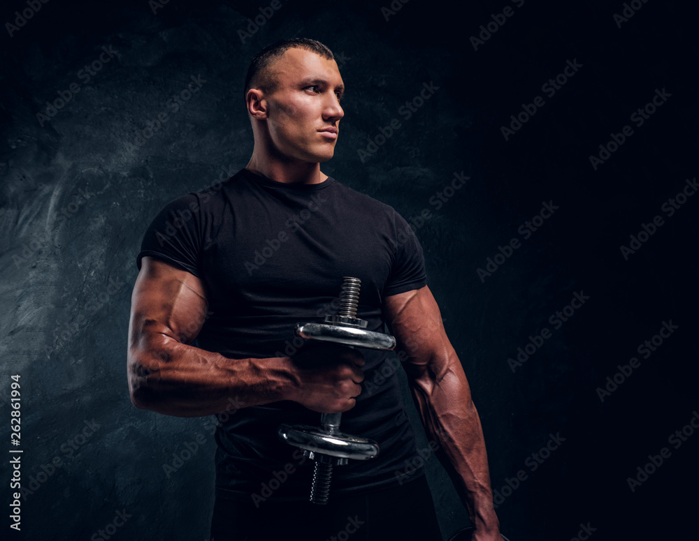 Muscular attractive bodybuilder lifting a dummbbell Muscular attractive bodybuilder lifting a dummbbell