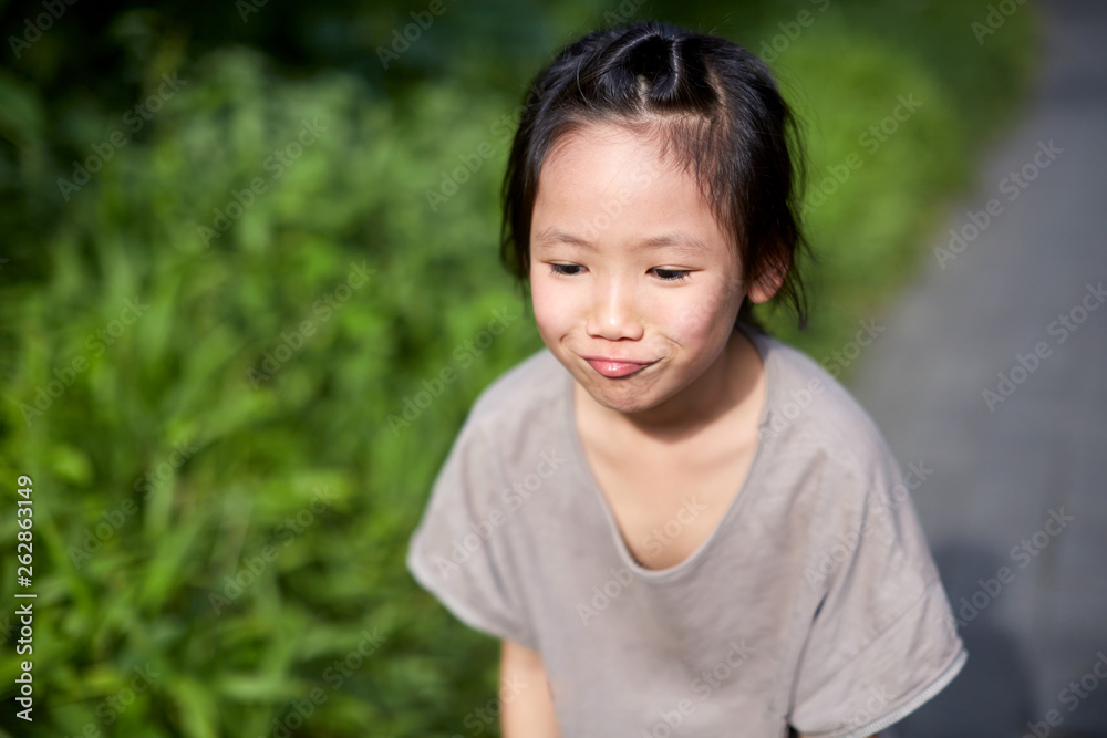 Cute Asian little girl with a naughty expression in the fields of Southeast Asian countryside Cute Asian little girl with a naughty expression in the fields of Southeast Asian countryside