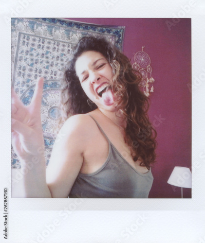 Brunette girl with curly hair sticking out tongue and showing pe photo