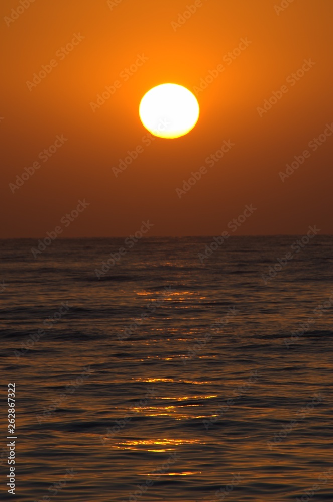 Sunset with large yellow sun under the sea surface