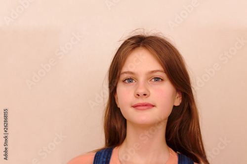 blue eyed brown haired shy girl in denim overalls. Studio model shot.