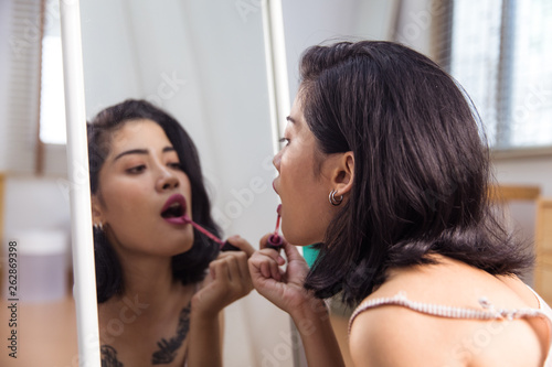 Beautiful Asian woman applies makeup in the mirror
