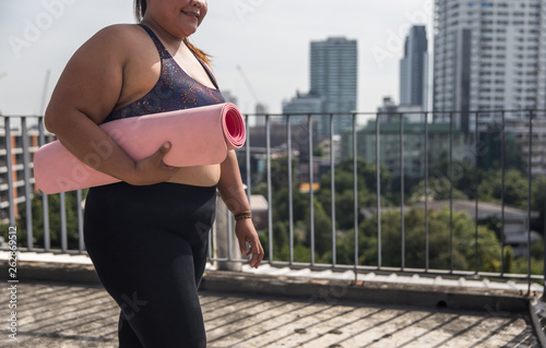 Faceless Woman Walks with Yoga Mat Under Arm photo