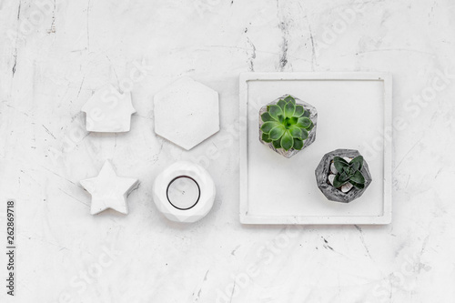 Work desk design with concrete decorations, candle and plant on marble background top view